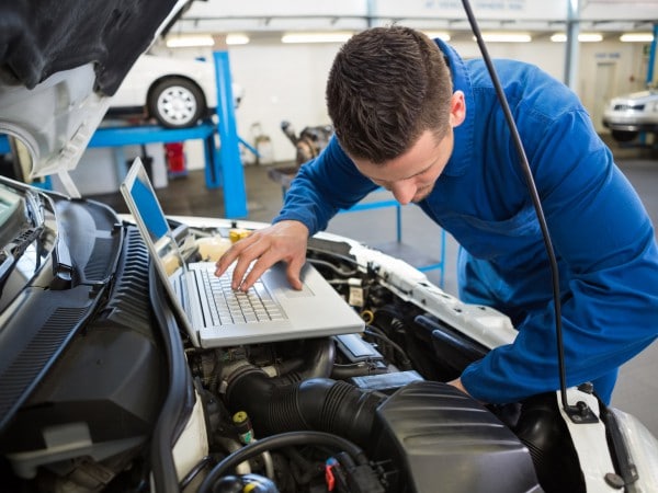 Mechanic using laptop on car at the repair garage